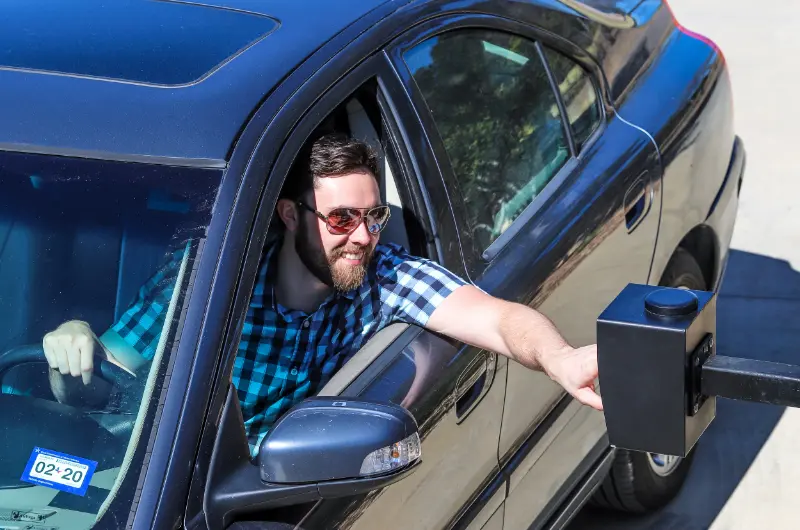 man entering number on outdoor keypad while seated in car cellgate watchman entry product gate access