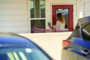 a woman using a key fob to enter a multi-family property from the exterior