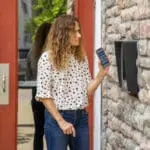 entry control systems with a woman using a QR code virtual key at a building entrance - access control systems with CellGate watchman product access control solution for multi-family and multifamily properties