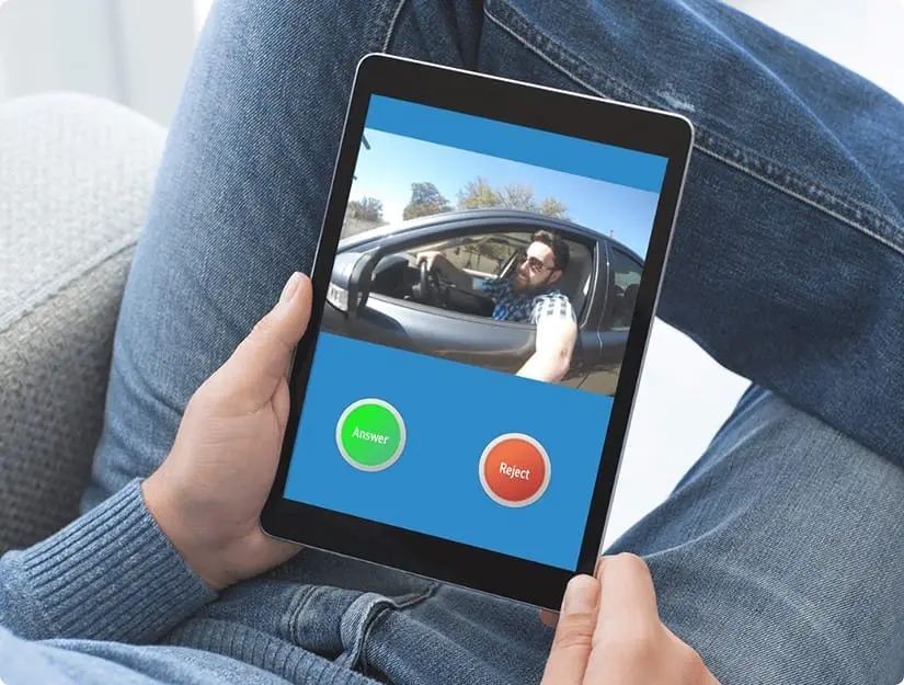 Individual using a tablet with the CellGate app showing a live video feed of a visitor at the gate with options to 'Answer' or 'Reject' the call