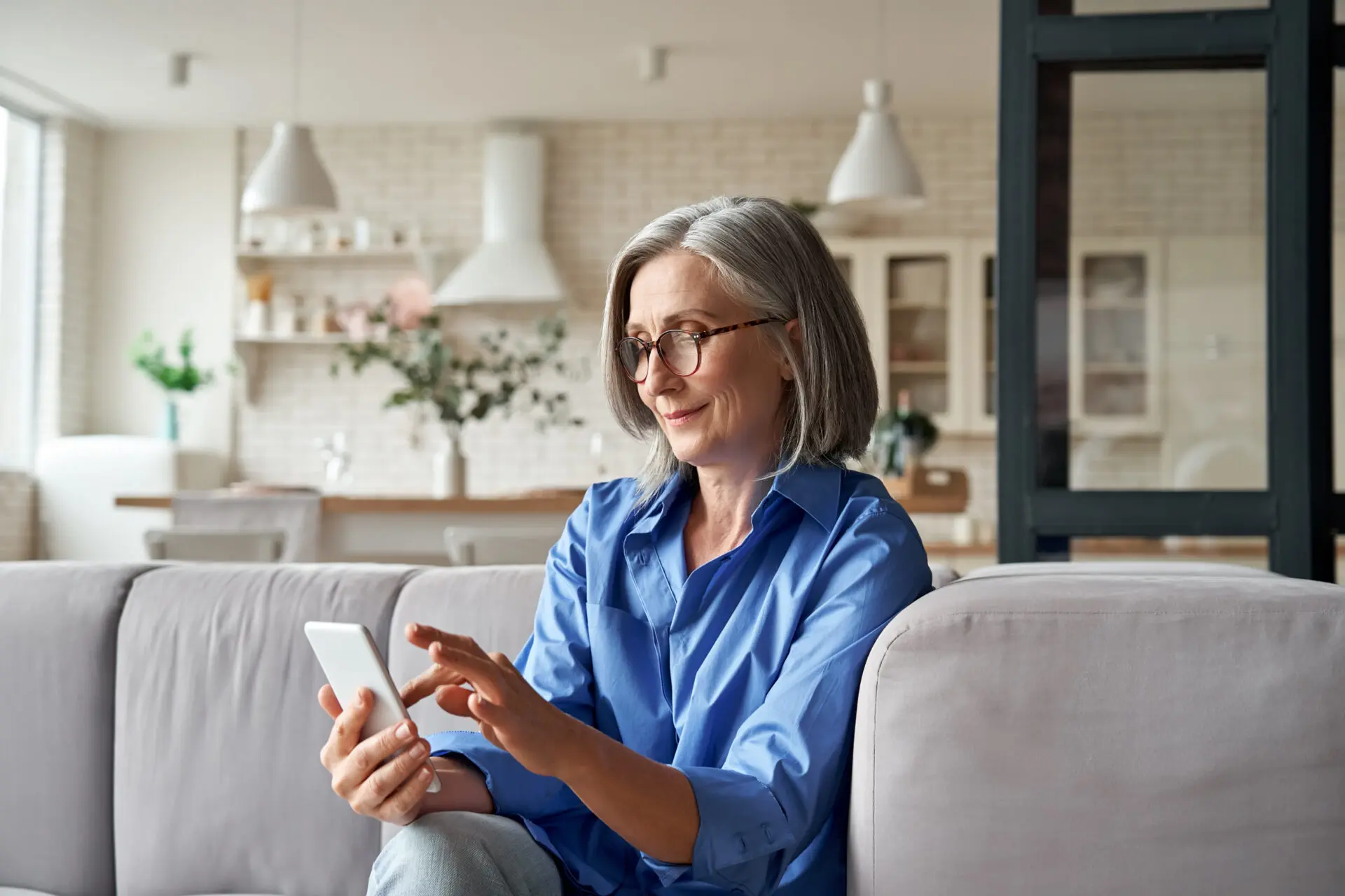 A relaxed mature woman looking at her smart phone in her home