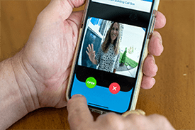 Person holding smartphone with CellGate app live video call showing visitor