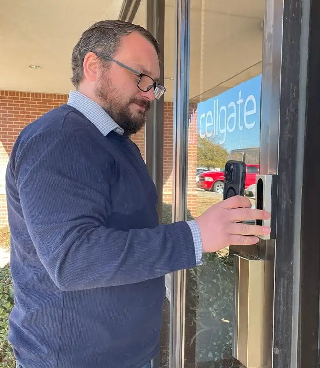Man using CellGate access control keypad at commercial building glass door entrance