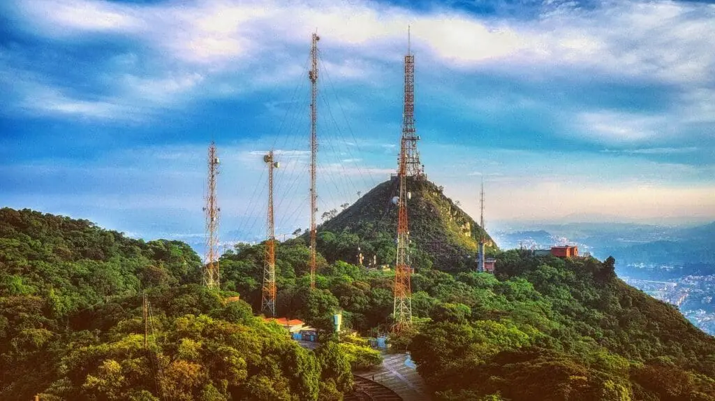 Cellular network towers on hilltop with antennas against blue sky