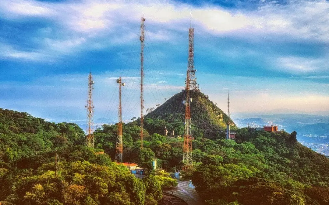 Cellular network towers on hilltop with antennas against blue sky